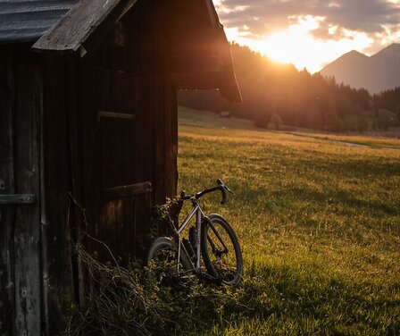 Blick auf ein Gravelbike an einer Hütte | © PAT:ART