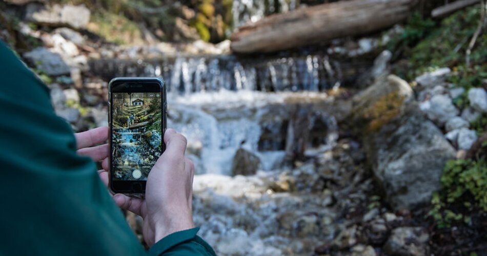 Blick auf einen Wasserfall am Philosophenweg in Garmisch-Partenkirchen durch eine Smartphone-Kamera | © GaPa Tourismus GmbH/ Roadtrip the World