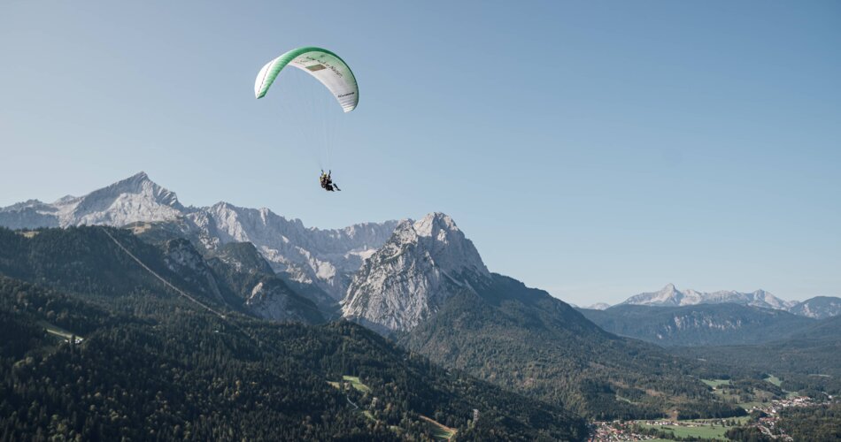 Gleitschirmflug mit Alpspitze und Wettersteinmassiv im Hintergrund | © FlyGarmisch/Tobias Dippon