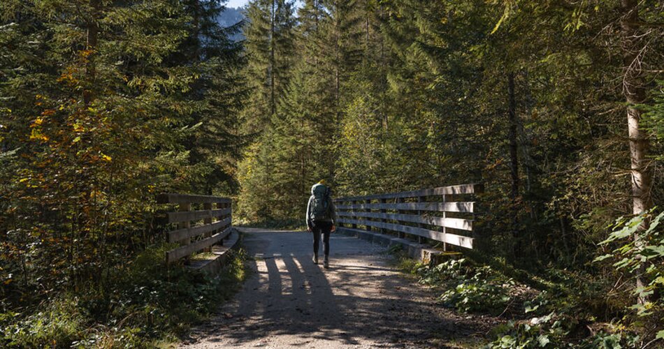 Blick auf eine Frau beim Wandern auf einer Brücke bei einer Wanderung durch das Reintal in Garmisch-Partenkirchen im Herbst  | © GaPa Tourismus GmbH/ Roadtrip the World